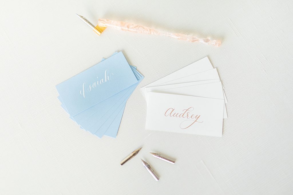Gold and white names written on wedding place cards with pen tips and calligraphy pens written by Ashley Thompson.